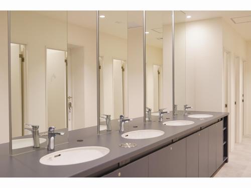 a row of sinks in a bathroom with mirrors at Capsule Hotel City Cabin Susukino in Sapporo