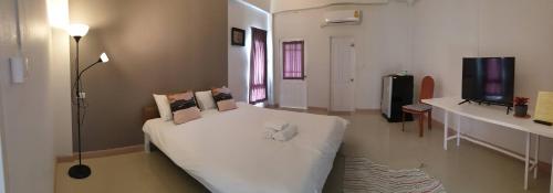 um quarto com uma cama branca e uma televisão em Prinya house ปริญญา เฮ้าส์ em Ban Huai Kapi