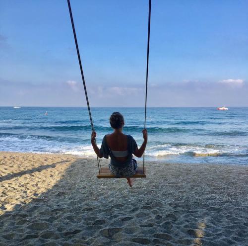a person sitting on a swing at the beach at Gold Twins Boutique Hotel in Alanya