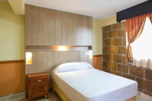 1 dormitorio con cama blanca y pared de ladrillo en OYO Hotel San Agustin en Acambay