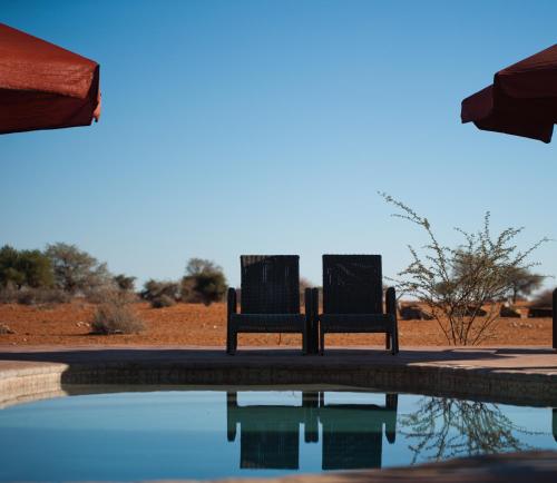 twee stoelen naast een zwembad met water bij Kalahari Anib Campsite in Hardap