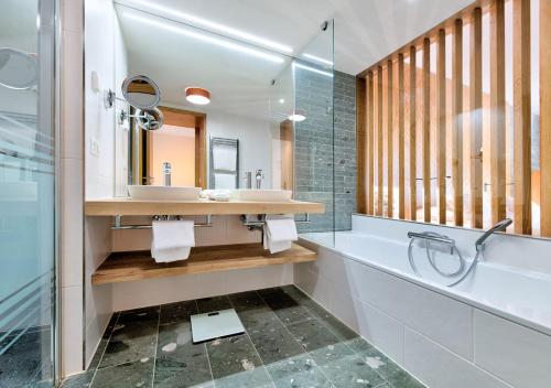 a bathroom with a tub and a sink and a mirror at Hôtel des Bains de Saillon in Saillon