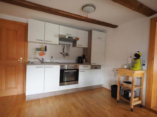 a kitchen with white cabinets and a wooden floor at Haus Fiel in Dornbirn