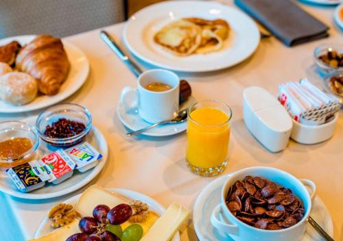 a table topped with plates of breakfast foods and orange juice at Hôtel des Bains de Saillon in Saillon