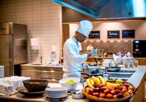 a chef preparing food in a kitchen with fruits and vegetables at Hôtel des Bains de Saillon in Saillon