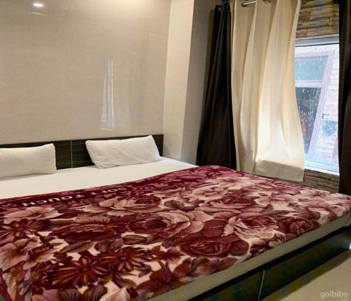 a bedroom with a bed with a red floral blanket at Hotel Star Light in Amritsar