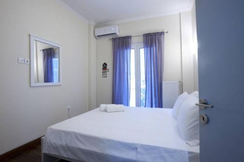 Schlafzimmer mit einem weißen Bett und blauen Vorhängen in der Unterkunft Comfortable apartment at the foot of the Odeon of Herodes Atticus in Athen