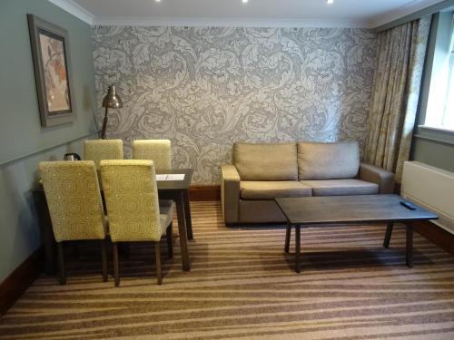 a living room with a couch and a table and chairs at The Stanneylands in Wilmslow