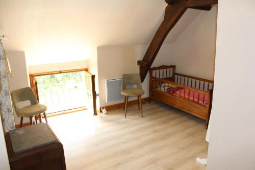 - une chambre avec un lit bébé et des chaises dans l'établissement chez Jeannette, à Marcillac-Saint-Quentin