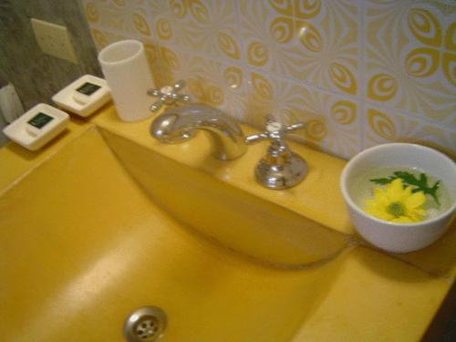 a yellow bathroom sink with a bowl of flowers on it at Palermo Viejo Bed & Breakfast in Buenos Aires