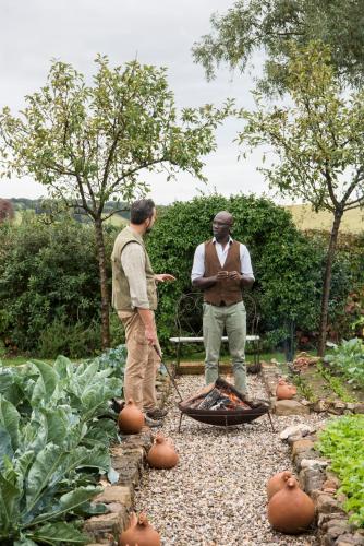 two men standing in a garden with a grill at Relais Sant'Elena in Bibbona