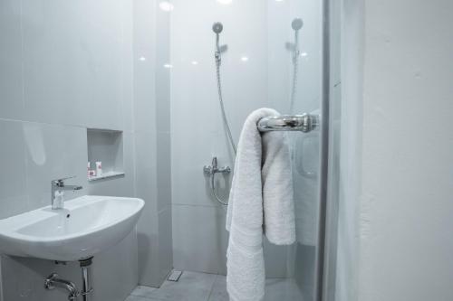 ein weißes Bad mit einem Waschbecken und einer Dusche in der Unterkunft OYO 1487 Residence Khoe in Jakarta