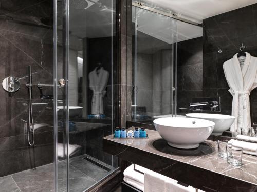 a bathroom with a sink and a glass shower at Sofitel Athens Airport in Athens