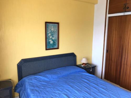 Schlafzimmer mit einem Bett mit blauer Bettwäsche und einem Bild in der Unterkunft Embajador 9 21 in Platja  d'Aro