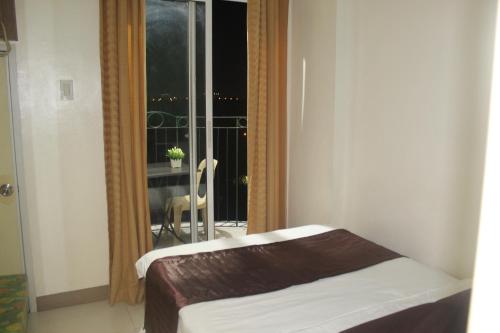 um quarto com uma cama e uma janela com uma varanda em CHATEAU ELYSEE A10 near airport em Manila