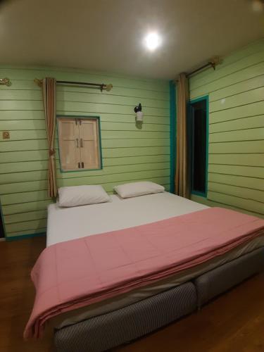 a bedroom with a large bed with a pink blanket at Baan Chan Sabai in Chanthaburi