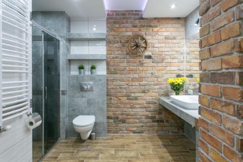 a bathroom with a brick wall and a toilet and a sink at VIP Apartamenty Stara Polana in Zakopane