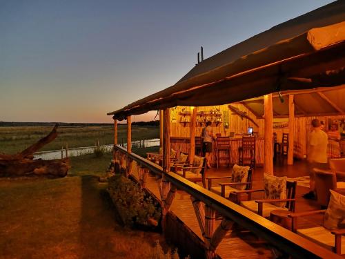 a restaurant with tables and chairs on a wooden deck at Chobe River Campsite in Ngoma