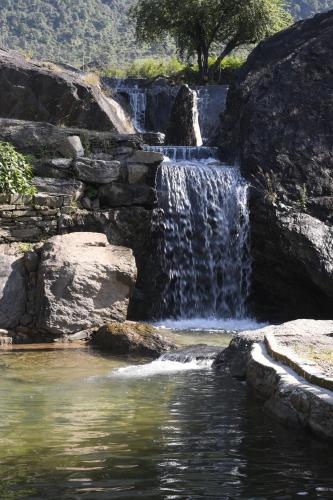 a waterfall in front of a pool of water at Hill Ventures Adventure Camp and Restaurant in Dharamshala