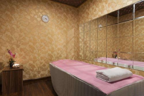 - une chambre dotée d'un lit avec des draps roses et un miroir dans l'établissement Howard Johnson by Wyndham Abu Dhabi Downtown, à Abu Dhabi
