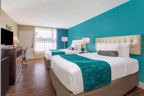 two beds in a hotel room with blue walls at Howard Johnson by Wyndham Lakeland in Lakeland