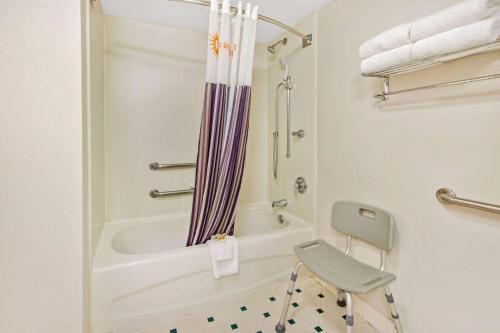 a bathroom with a tub and a chair in it at La Quinta by Wyndham Albuquerque West in Albuquerque