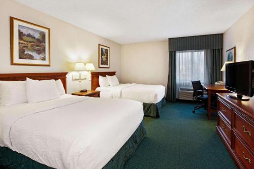 a hotel room with two beds and a desk and a television at La Quinta Inn by Wyndham Detroit Canton in Canton