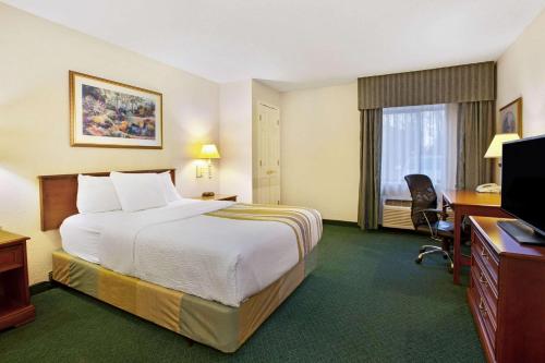 a hotel room with a bed and a desk and a television at La Quinta Inn by Wyndham Detroit Canton in Canton