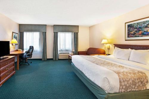 a hotel room with a large bed and a desk at La Quinta Inn by Wyndham Detroit Canton in Canton