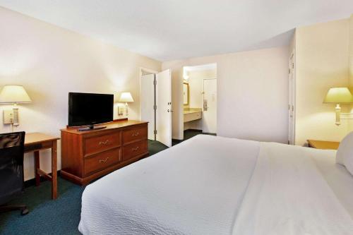 a hotel room with a bed and a flat screen tv at La Quinta Inn by Wyndham Detroit Canton in Canton