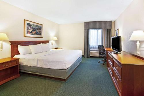 a hotel room with a bed and a desk at La Quinta Inn by Wyndham Detroit Canton in Canton