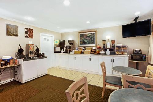 a kitchen with white cabinets and a table and chairs at La Quinta Inn by Wyndham Detroit Canton in Canton