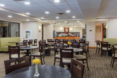 a dining room with tables and chairs and a cafeteria at La Quinta by Wyndham Garden City in Garden City