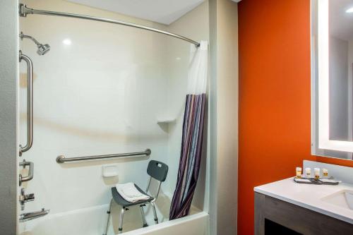a bathroom with a shower and a chair next to a sink at La Quinta by Wyndham Pittsburg in Pittsburg
