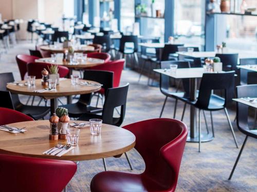 a restaurant with tables and red chairs and tablesktop at Novotel Edinburgh Centre in Edinburgh