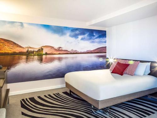 a bedroom with a painting of a castle in the water at Novotel Edinburgh Centre in Edinburgh