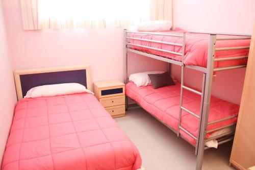 2 Etagenbetten in einem Zimmer mit rosa Bettwäsche in der Unterkunft Sol Daurat seafront apartment in Cambrils