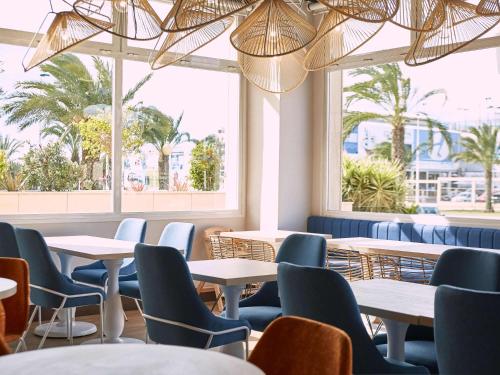 Un restaurante con mesas, sillas y ventanas. en Ibis Elche, en Elche