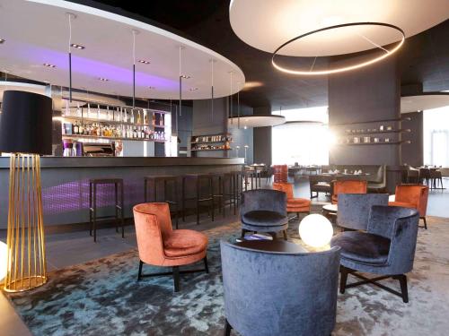 a lobby with a bar with chairs and tables at Novotel Basel City in Basel