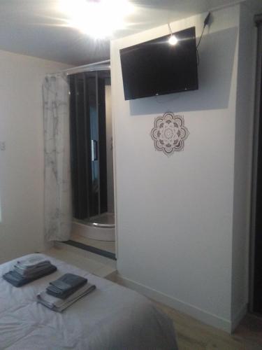 1 dormitorio con 1 cama y TV en la pared en Le Corto, en Savigny-Lévescault