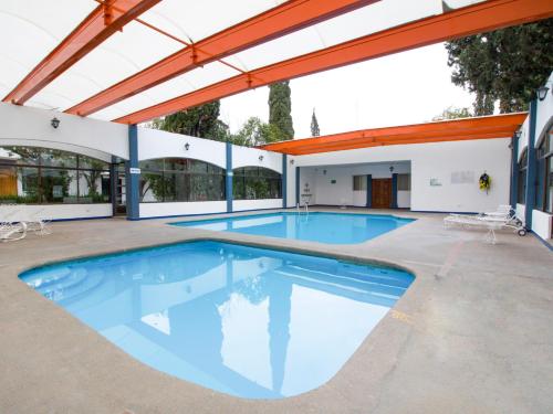 a large swimming pool in a building with awning at Hotel La Fuente, Saltillo in Saltillo
