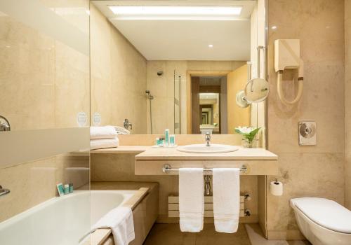 een badkamer met een wastafel, een bad en een toilet bij Ilunion Pio XII in Madrid