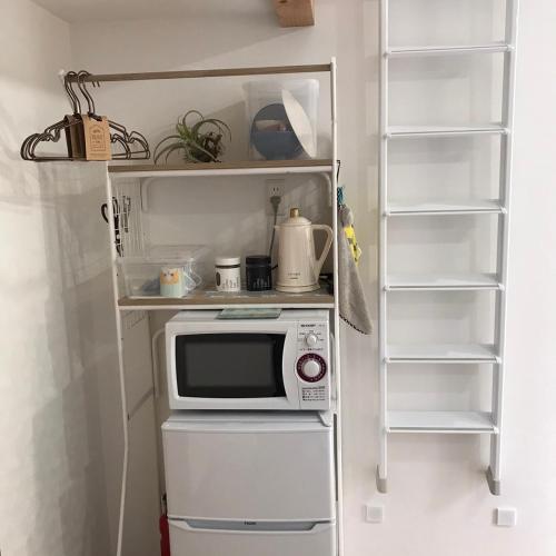 a small kitchen with a microwave and shelves at Stay Nikko Guesthouse in Nikko