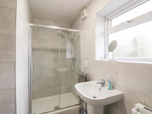 a white bathroom with a shower and a sink at Meadowbank in Girvan