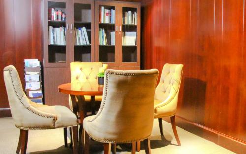 three chairs and a table in a room with a book shelf at City Hotel Xiamen-Free Welcome Fruits in Xiamen