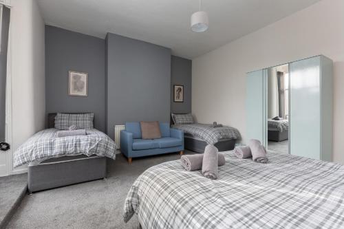 um quarto com 2 camas e uma cadeira azul em Raikes Parade Victorian Holiday Home - Blackpool Resort Collection em Blackpool