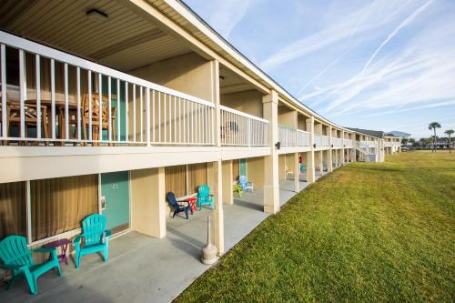 a patio area with chairs, tables, and benches at Days Inn & Suites by Wyndham Jekyll Island in Jekyll Island