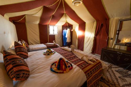 a bedroom with a large bed with two animals laying on it at Sahara Luxury Desert Camp in Merzouga
