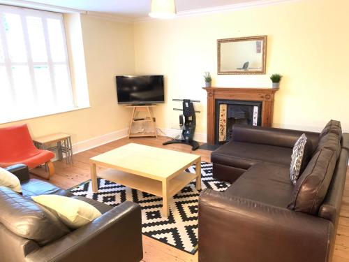 a living room with leather furniture and a fireplace at MyCityHaven South Parade Mansions in Bristol