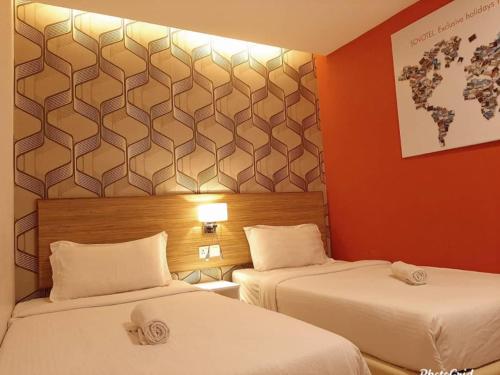 two beds in a hotel room with red walls at Sovotel @ Kota Damansara 8 in Kota Damansara
